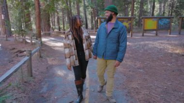 Yosemite Ulusal Parkı 'nda, etrafı ağaçlarla çevrili, sakin bir atmosferde gezen, baş döndürücü doğal güzelliklerinin ve çevrelerindeki huzurun tadını çıkaran bir çift.