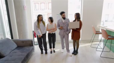Modern bir ofiste, yetenekli profesyonellerden oluşan çeşitli bir grup dizüstü bilgisayar kullanarak önemli konular üzerinde işbirliği yaparak, kendi alanlarında takım çalışmasına ve mükemmelliğe olan bağlılıklarını sergiliyor.