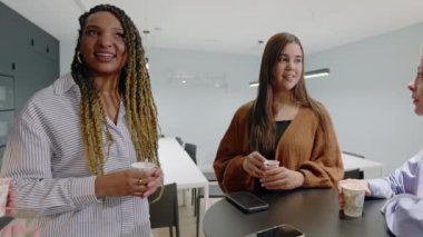 Modern bir ofiste, çeşitli bir grup kahve molasından zevk alır, işbirliğini, yaratıcılığı ve iletişimi teşvik eder. Bu dinamik ayar takım çalışmasını, motivasyonu ve profesyonel ilişkileri geliştirir