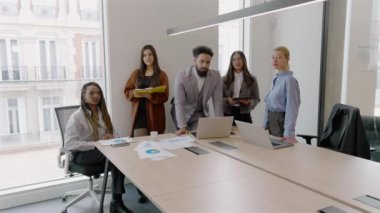 Modern ofis ortamı, çeşitli ciddi ve yetenekli profesyonellerden oluşan bir grup laptopu etkin bir şekilde kullanırken, takım çalışmasının ve ortak çabaların önemini vurgulamak için bir araya geliyor.