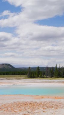 Yellowstone 'un çarpıcı jeotermal özelliklerini keşfedin, canlı mavi sular ve yemyeşil ile Wyoming' de dinamik bir gökyüzüne karşı kurulmuş engin bir vahşi doğa, keşfedilmeye hazır bir açık cennet.