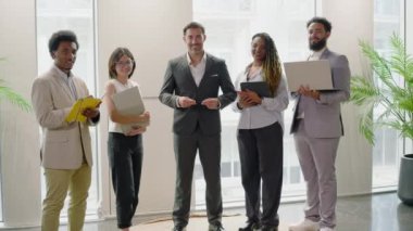 Modern ofiste üst düzey profesyonellerden oluşan çeşitli gruplar sıralanır. Çok ırklı profesyonel yönetici grubu şirket portresi ve liderlik için birlikte poz veriyor. Yavaş çekim