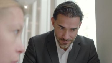 Ortak bir ofiste çeşitli iş adamları arasındaki dinamik etkileşim, ortak hedeflere ve ortak hedeflere başarılı bir şekilde ulaşmak için takım çalışmasının önemini vurgulamaktadır.