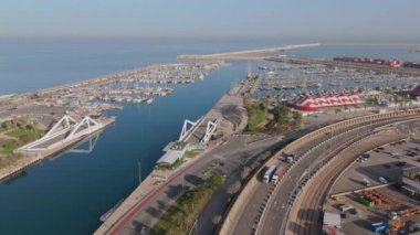 Valencia Limanı, marina ve işlek caddelerin hava görüntüsü arabalar ve kamyonlar, renkli konteynırlar, yüksek vinçler, ticari merkezleri tanımlayan hareketli nakliye faaliyetlerine katılan gemiler.