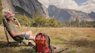 Yürüyüşçü Yosemite Milli Parkı 'nda dinleniyor. Etrafı nefes kesici doğa güzelliği manzaralarıyla çevrili. Sırt çantaları önlerindeki heyecan verici macera ve keşfe hazır.