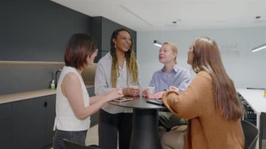Çeşitli başarılı iş kadınlarından oluşan bir grup, şık, modern bir ofis masası etrafında coşkuyla canlı bir tartışmaya girişerek, birbirleri arasında işbirliğini ve takım çalışmasını aktif bir şekilde teşvik ediyorlar.
