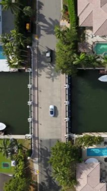 Sinema sahnesi, Miami Beach, Florida 'nın güneyindeki güzel evleri, parlak havuzları ve kanalizasyon adalarının etrafındaki su yollarına kenetlenmiş çeşitli tekneleri gösteriyor.