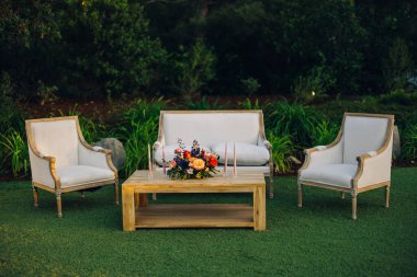 Bu büyüleyici açık alan şık bir kanepe, rahat koltuklar ve ahşap bir masanın üzerinde çiçek süsü içeriyor, hepsi yemyeşil, dinlenmek ve toplanmak için sakin bir alan yaratıyor.