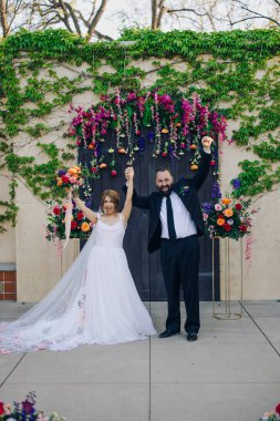 Güzel ve canlı bir çiçek arkaplanının ortasında, mutlu bir çift evliliklerini sevinçle kutluyor, düğünlerini aileleri ve arkadaşlarıyla birlikte kutluyorlar.