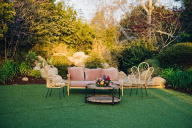 Zarif bir şekilde tasarlanmış, şık mobilyaları olan, sakin bir bahçede güzelce yerleştirilmiş, toplanma, etkinlikler veya basitçe rahatlama ve keyif için ideal bir yer haline getiren bir açık hava oturma alanı.