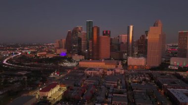 Çarpıcı hava görüntüsü, Houston, Teksas şehir merkezinin canlı ve hareketli manzarasını güzel bir şekilde yakalıyor, çarpıcı modern mimariyi ABD 'nin büyüleyici alacakaranlık gökyüzüne karşı sergiliyor.