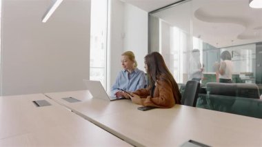 Modern bir ofis alanında, çeşitli profesyonellerden oluşan bir ekip etkin bir şekilde işbirliği yapmak için bir araya gelirler, canlı ve pozitif bir çalışma ortamı çizerler, aynı zamanda görevleri için bir dizüstü bilgisayar kullanırlar.