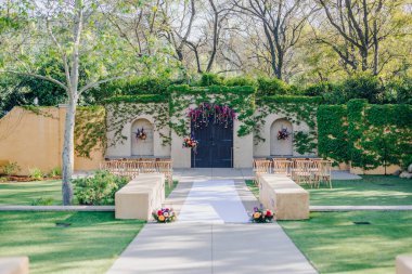 Bu çarpıcı açık hava düğün mekanında yemyeşil, dekoratif çiçekler ve zarif bir şekilde yerleştirilmiş koltuklar var. Güzel bir aşk ve birliktelik kutlaması için mükemmel bir zemin oluşturuyorlar.