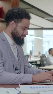 Kendini işine adamış ve çalışkan bir iş adamı tamamen bilgisayarına odaklanırken, aynı zamanda çağdaş bir ofis ortamında, dinamik bir çalışma alanı içinde olağanüstü üretkenlik sergiliyor.