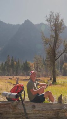 Yosemite Ulusal Parkı 'nın nefes kesen ve sakin yerinde, erkek bir yürüyüşçü, çevresini saran görkemli dağlar ve bereketli ağaçlarla çevrili doğanın sükuneti ve güzelliğiyle eğlenir.