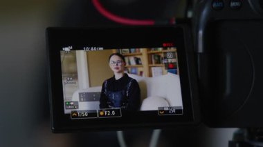 Beyaz tenli, esmer kadının yakın çekimi büyüleyici iç mekan içinde gözlüklerle röportaj veriyor. Siyah kıyafetli bir bayanın kamera ekranından göründüğü bir video kaydı. Yüksek kalite 4k görüntü