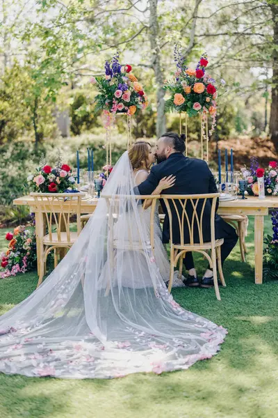 Sevgi dolu bir çift, bu özel günü neşe ve aşkla kutlamak için canlı çiçeklerle çevrili açık hava düğün törenlerinde samimi bir anı paylaşır.