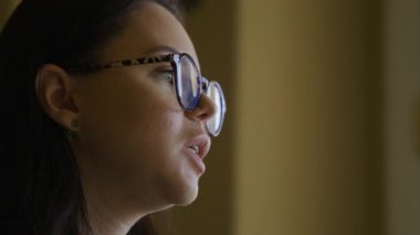 Antik iç mekanlarda gözlüklü ve şık giyinmiş bir kadının profiline yakın çekim. 30 'lu yaşlarda beyaz, yetişkin bir kadın röportaj veriyor. Video kaydı. Yüksek kalite 4k