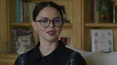 Siyah elbiseli ve antika gözlüklü bir kadının yakından görüntüsü. 30 'lu yaşlarda beyaz, yetişkin bir kadın röportaj veriyor. Video kaydı. Yüksek kalite 4k