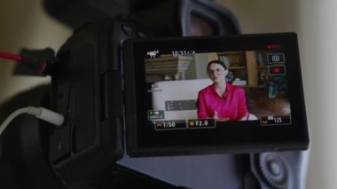 Beyaz tenli, esmer bir kadının kamera önünde yakın plan çekimleri büyüleyici iç mekanlar içinde gözlüklerle röportaj veriyor. Şık giyinmiş bir bayanın video kaydı. Yüksek kalite 4k görüntü