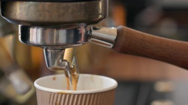 Kahve makinesinin taze ve lezzetli bir sabah içeceği yaptığını ayrıntılı bir şekilde görmek. Barista 'nın elinde sıcak buharla kağıt bardak tutarken yakın plan fotoğrafı. Yüksek kalite 4k görüntü