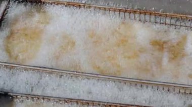 Yüksek sıcaklıkta yağda kızartılmış yemeğin detaylı görüntüsü. Dışarıdaki lezzetli fast food için bir fritözün yakın çekim görüntüsü. Yüksek kalite 4k görüntü