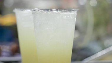 Tanınmayan birinin taze, ışıl ışıl limonata yaparken yakın plan fotoğrafı. Beyaz bir kadının elinde bir fincan soğuk, lezzetli içecek tutarken detaylı görüntüsü. Yüksek kalite 4k görüntü