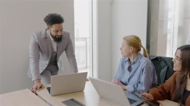 Çağdaş bir ofis ortamında, üretken bir toplantı sırasında çeşitli yetenekli profesyonellerden oluşan bir grup, her biri laptoplarına odaklanmış ve çeşitli yenilikçi fikirleri aktif olarak tartışıyor.