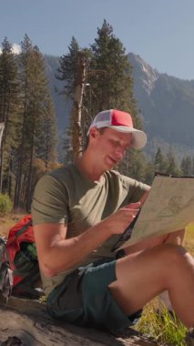 Yosemite Milli Parkı 'nın çarpıcı güzelliğinin tadını çıkarırken bir adam harita üzerinde çalışıyor. Doğal güzellikler ve heyecan verici maceralar bu açık hava cennetinde uyum içinde bir araya geliyor.