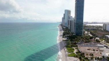 Miami Sahili 'nin ve ikonik siluetinin çarpıcı bir görüntüsünü tecrübe edin. Bu lüks seyahatin nefes kesici sahil şeridinin ve hayat dolu atmosferinin tadını çıkarın. Dünya çapında ziyaretçileri cezbediyor.