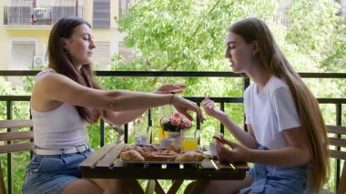 Mutlu bir ailenin balkonda otururken taze hamur işi yediği yakın plan bir fotoğraf. Kafkasyalı kadınların sohbet edişlerinin ve mutlu görünmelerinin portresi. Yüksek kalite 4k görüntü