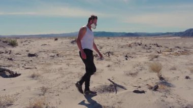 Issız bir çöl manzarasında, solunum maskesi takan dayanıklı bir adam, kıyamet gibi bir dünyada hayatta kalmanın ve direnmenin güçlü bir sembolü olarak, ezici zorluklarla ve zorluklarla savaşır.