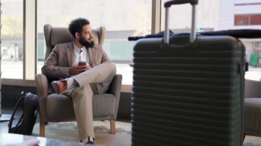 Zarif Afro-Amerikan erkeği, çağdaş bir alanda, düzenli bavulunun yanında, heyecanla heyecanlı bir macera beklerken inkar edilemez bir cazibe sergiliyor. 