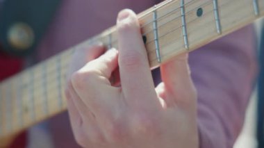Gitar çalmaya yakın çekim. Akustik gitar tıngırdatıyorum. Müzisyen müzik çalar. Erkek parmakları arabulucuyu tutuyor. Dışarıda gitar çalan bir adam. Kişi provası, fretboard yakın çekim. Yüksek kalite 4k