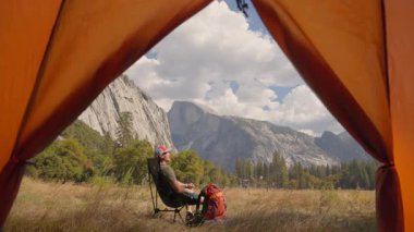Yosemite Ulusal Parkı 'nda geçen bu resimli kamp sahnesinde dağ manzaralarının nefes kesici güzelliği, bir karşılama çadırı ve huzur içinde doğaya dalmış bir sırt çantasının ihtişamı görülüyor.