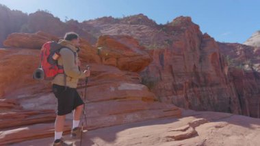 Afro-Amerikalı bir erkek büyüleyici Zion Ulusal Parkı 'nda heyecanlı bir şekilde yürüyüş yapıyor, nefes kesici manzaralar ve göz alıcı kaya oluşumları sergiliyor.
