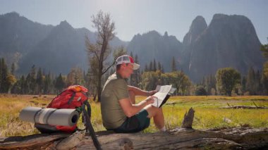 Kendini adamış yürüyüşçü Yosemite Ulusal Parkı 'nın çarpıcı manzarasının ortasında bir topoğrafik harita üzerinde çalışıyor, ikonik El Capitan ve Half Dome doğa aşıkları için mükemmel bir deneyim yaratıyor.