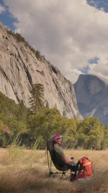 Yoğun hayatından, Yosemite Ulusal Parkı 'nın nefes kesen güzelliğinin tadını çıkarmak için, nefes kesici doğal manzarası ve sakin atmosferinin ortasında bir sandalyede dinlenen bir adam hak ettiği molayı alıyor.