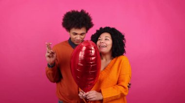 Sevgililer Günü 'nde ilk buluşmada genç erkek ve kız arkadaşın yakın çekimi. Kalp şeklindeki balonun keyfini çıkaran gençlerin portresi. Yüksek kalite 4k görüntü