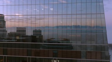 Los Angeles şehir merkezinin sakin sabah manzarası büyüleyici sis ve bulutların modern gökdelenlerin cam yüzeylerini güzel yansıtıp huzurlu bir şehir atmosferi yarattığını gösteriyor.