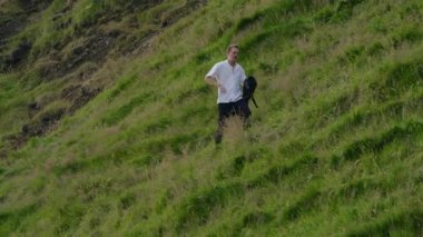 Genç adam yeşil çimlerin arasında sessizce yürüyor. Resmedilmeye değer bir yamaçta. Doğanın nefes kesen güzelliğini ve derin yalnızlık duygusunu gözler önüne seriyor.