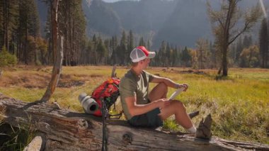 Tutkulu yürüyüşçü, Yosemite Milli Parkı 'nın nefes kesen güzelliğine dalmış, yüksek ağaçlar ve görkemli dağlarla çevrili bir topoğrafik harita üzerinde çalışıyor.