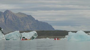 İzlanda 08.12.2023. İzlanda 'daki Jokulsarlon Buzul Gölü' nün çarpıcı güzelliğini deneyimleyin. Görkemli mavi buzdağları dramatik dağ manzaraları arasında yüzer ve olağanüstü bir görsel manzara yaratır.