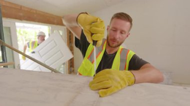 Hareketli bir inşaat sahasında, çeşitli müteahhitlerden oluşan bir grup, ev yenileme ve iyileştirme sürecinin karmaşık sürecinde takım çalışması ruhunu örnek göstererek büyük bir hevesle işbirliği yapıyor.