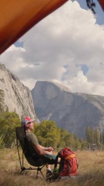 Bir adam rahat bir sandalyede oturup Yosemite Ulusal Parkı 'nın nefes kesici manzarasının tadını çıkarıyor. Unutulmaz bir açık hava macerası ve ömür boyu yaşatılacak seyahat deneyimleri için mükemmel bir yer.