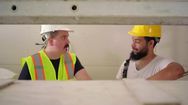 Yoğun bir inşaat alanında, iki usta inşaatçı yenileme planlarını tartışarak, proje başarısı ve ilgili herkes için kalite sonuçları için çeşitlilik ve takım çalışmasının önemini vurguladılar.