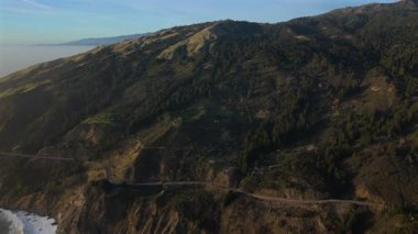 Gün batımında Big Surs sahil şeridinin çarpıcı hava manzarasını tecrübe edin. Unutulmaz deneyimler arayan maceraperest gezginler için bir ziyaret olan ikonik Otoyol 1 'in cazibesini vurgulayın.