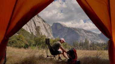 Yosemite Ulusal Parkı 'nın nefes kesici güzelliği erkek yürüyüşçüler güzel manzaralı kamp yaparken. Çadırının yanında, El Capitan ve Half Dome 'un çarpıcı ve etkileyici manzarasının keyfini çıkarın.