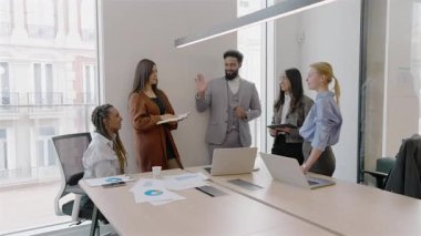 Modern bir ofis ortamında, yetenekli profesyonellerden oluşan çeşitli bir grup aktif olarak dinamik ve üretken bir tartışmaya katılarak etkili bir işbirliği, takım çalışması ve iletişimi örnek göstermektedir.