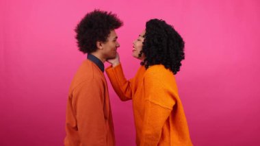 Erkek ve kadının kapalı mekanda romantik bir randevudaki yakın çekimi. Arkasında pembe izole edilmiş bir geçmişi olan erkek arkadaşını öpen bir kadının portresi. Yüksek kalite 4k görüntü